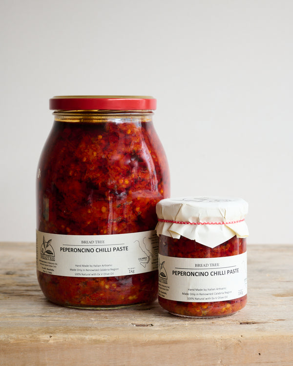 Two jars of Peperoncino Chilli tapenade, one large and one small, on a wooden surface.