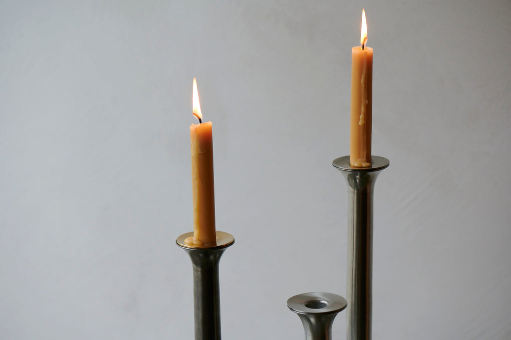 Pewter metal candlesticks with lit beeswax candles
