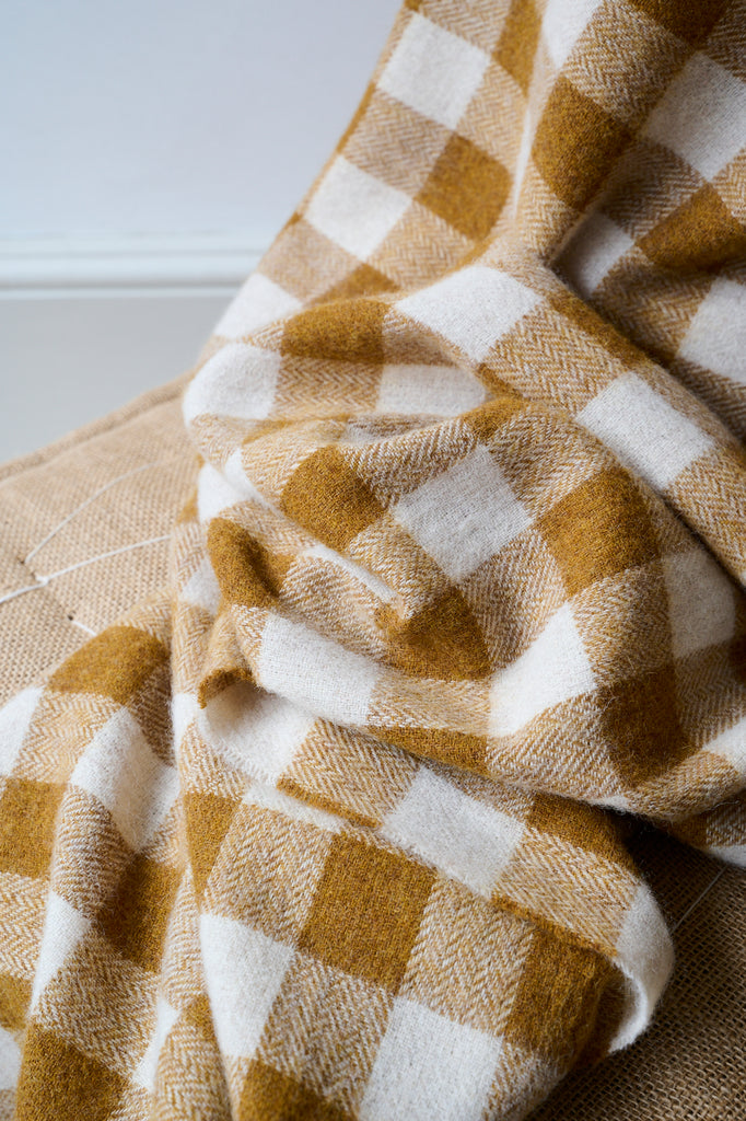 Close up of gingham blanket in ochre and cream, made from 100% lambswool.