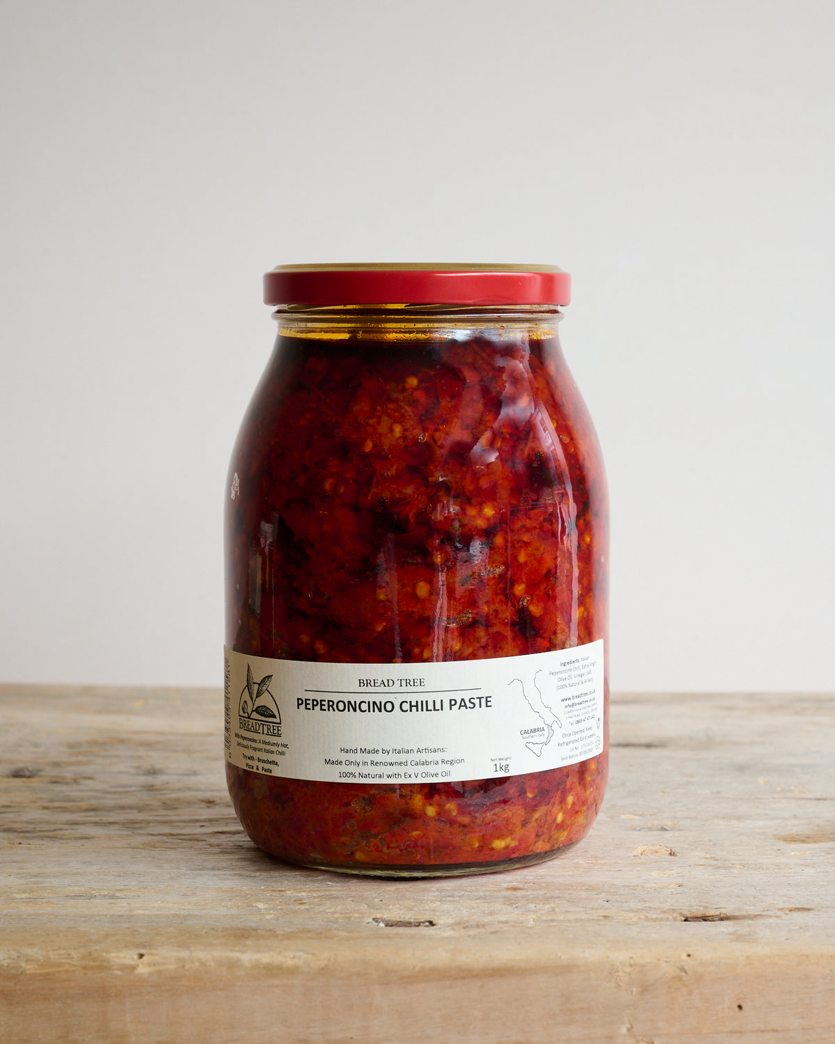 Large jar of Peperoncino Chilli tapenade on a wooden surface.