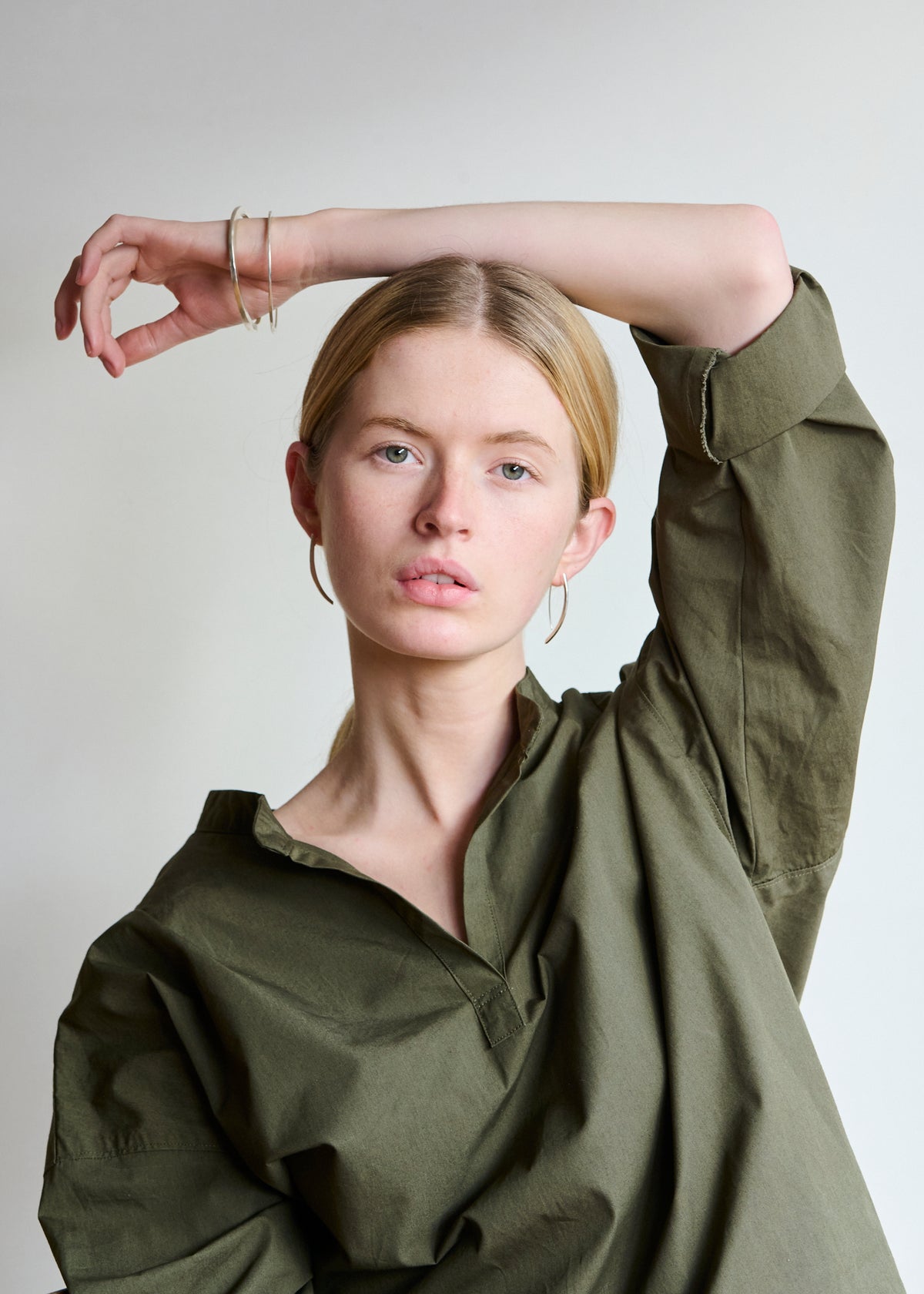 Women wearing and open collar dark green shirt with long silver earrings
