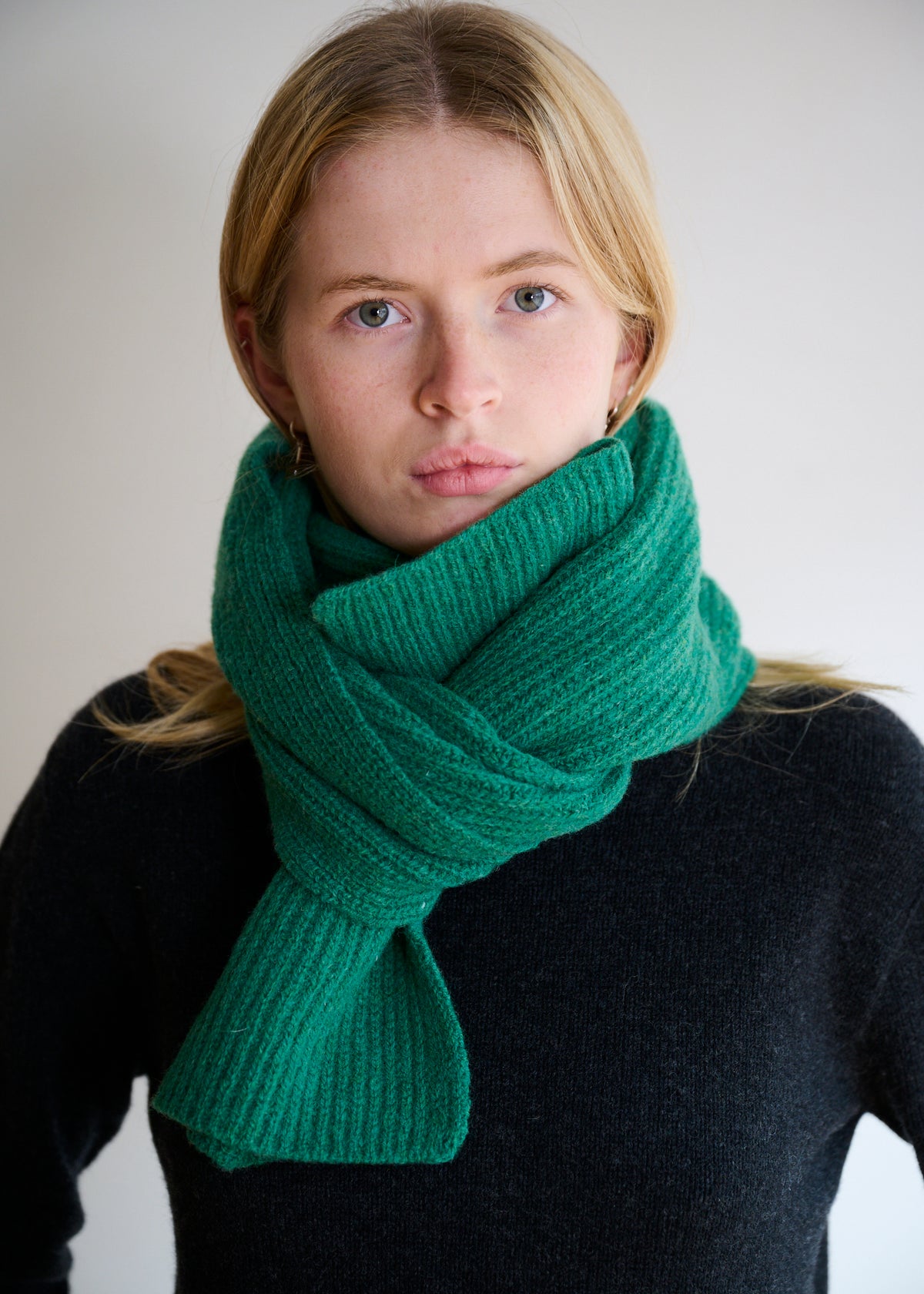 Person wearing a bright green lambswool scarf against a plain background
