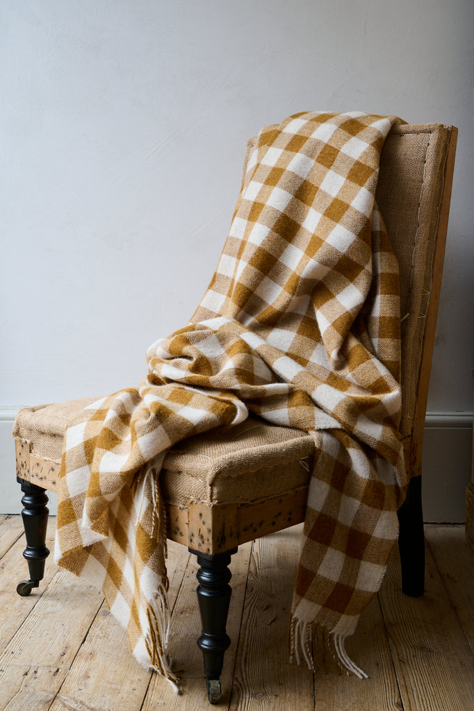 Soft wool blanket in ochre and cream, draped over an antique chair